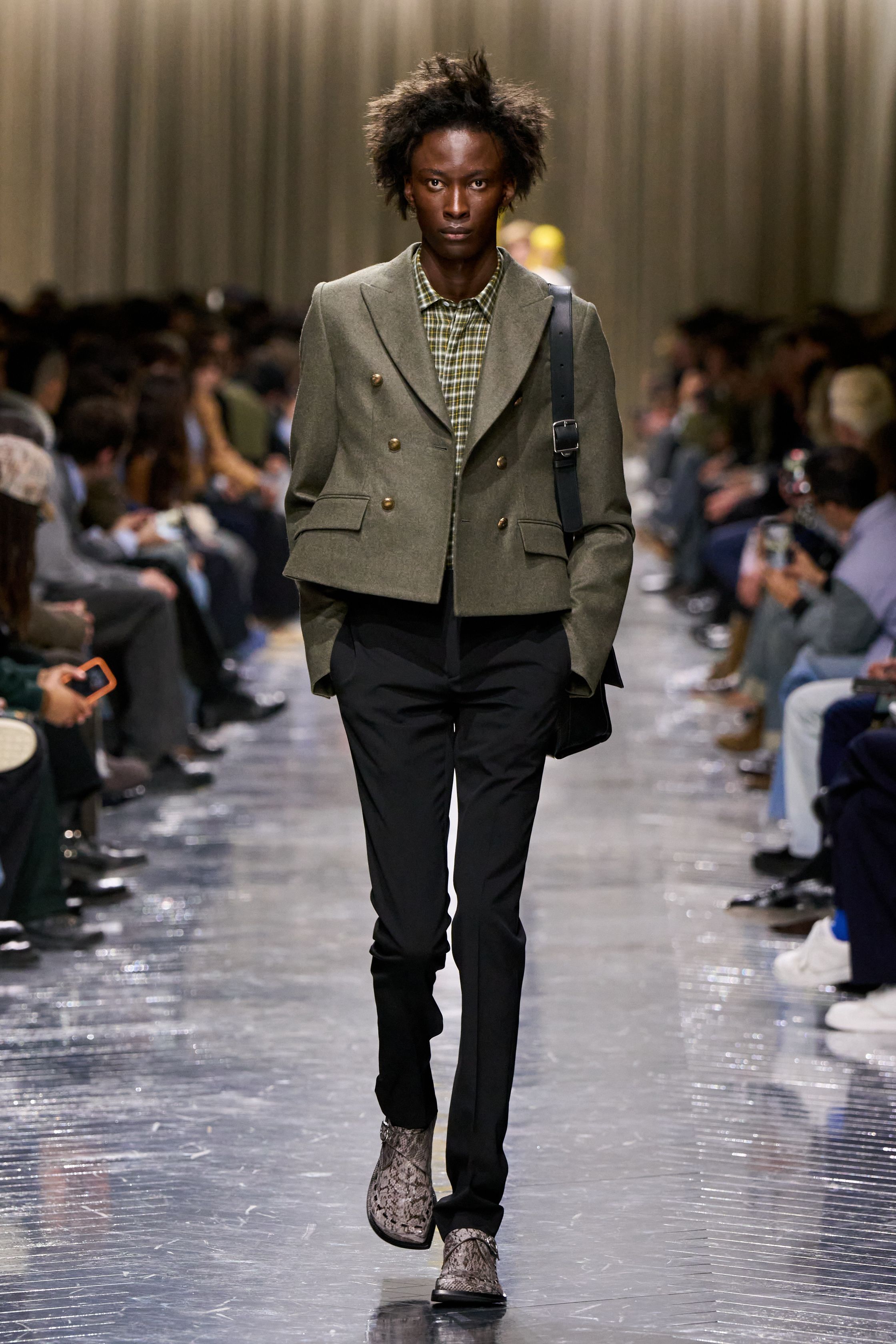 本季 Dior Men 2026 秋冬在克制与叛逆之间建立起新的男性气质坐标。轮廓上，柔软针织、披风式外套与军装结构形成张力对照，模糊正装与休闲、性别与功能的边界；材质层面，羊毛、皮革、毛绒与轻量技术面料并置，强化“触感叙事”。色彩从学院派的灰蓝、橄榄绿过渡至点状印花与手工肌理，传递一种被精心编排的随性。整体呈现出一种“新贵游牧者”形象：既有高级定制的工艺根基，又拥抱当代青年对自由、混搭与身份流动性的渴望-顽石频道趋势研究